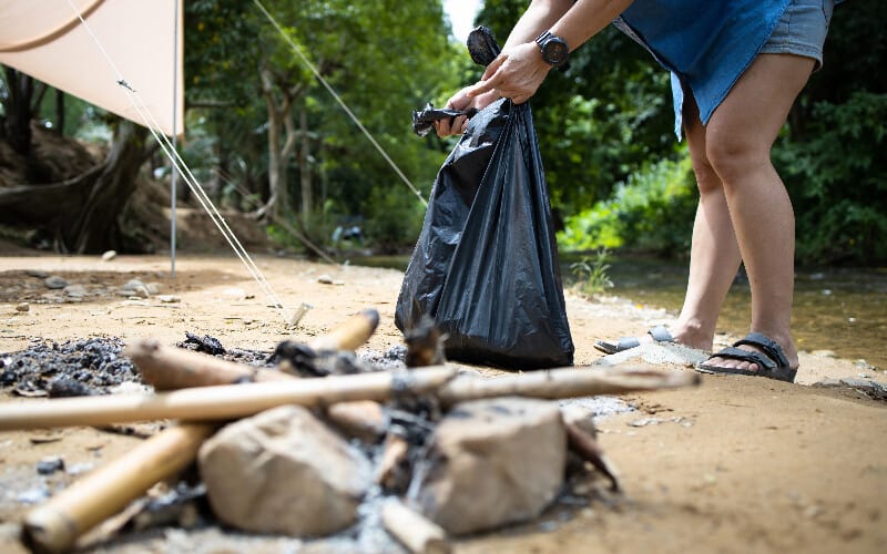 A person collecting trash at their campsite.